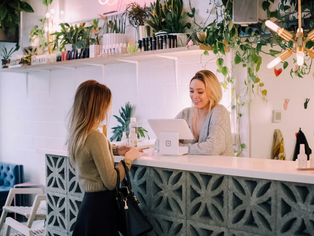 Front desk staff in branded corporate wear greeting a visitor